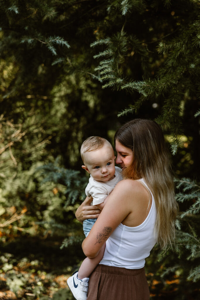 Baby verstopt zijn gezichtje in mama’s schouder tijdens een knuffelmoment.