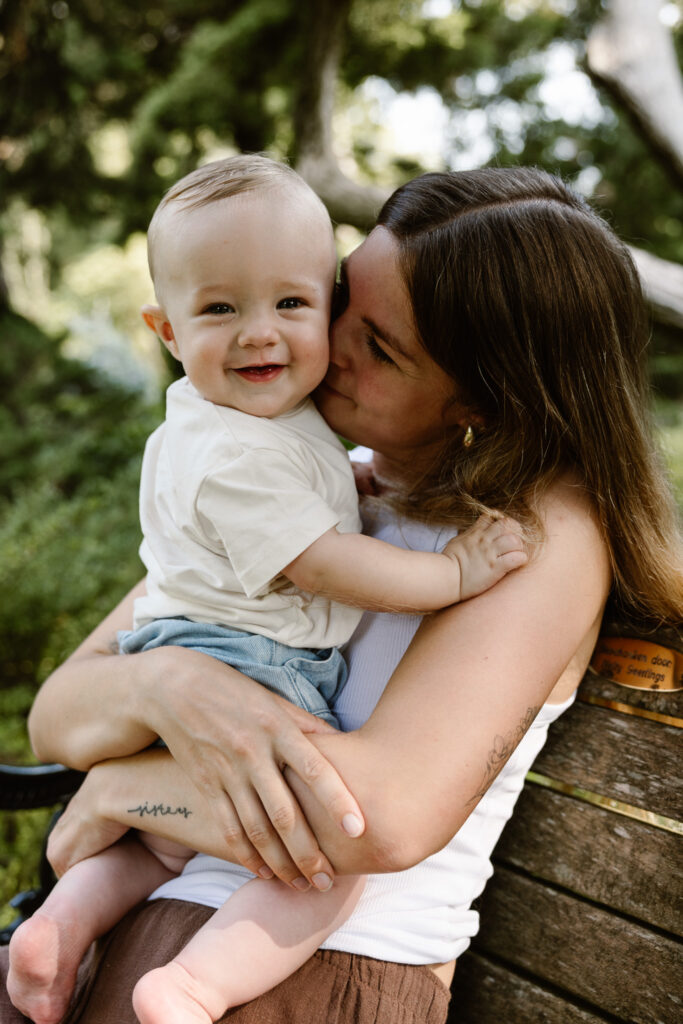 Sfeervolle lifestyle foto van moeder en kind zittend op een bankje in de tuinen.