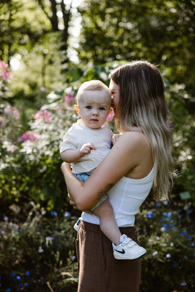 Close-up van een lachend jongetje van tien maanden dat tegen zijn moeder aanleunt tijdens een fotoshoot.