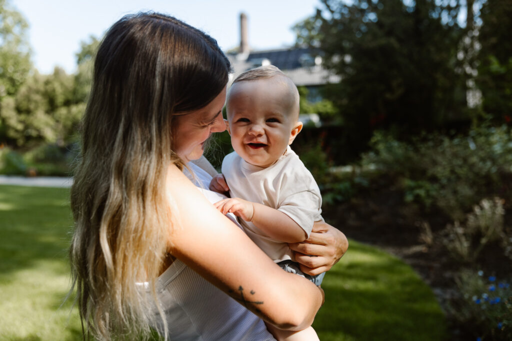 Mama knuffelt haar baby tijdens een ontspannen moeder-en-kind fotoshoot in de natuur.