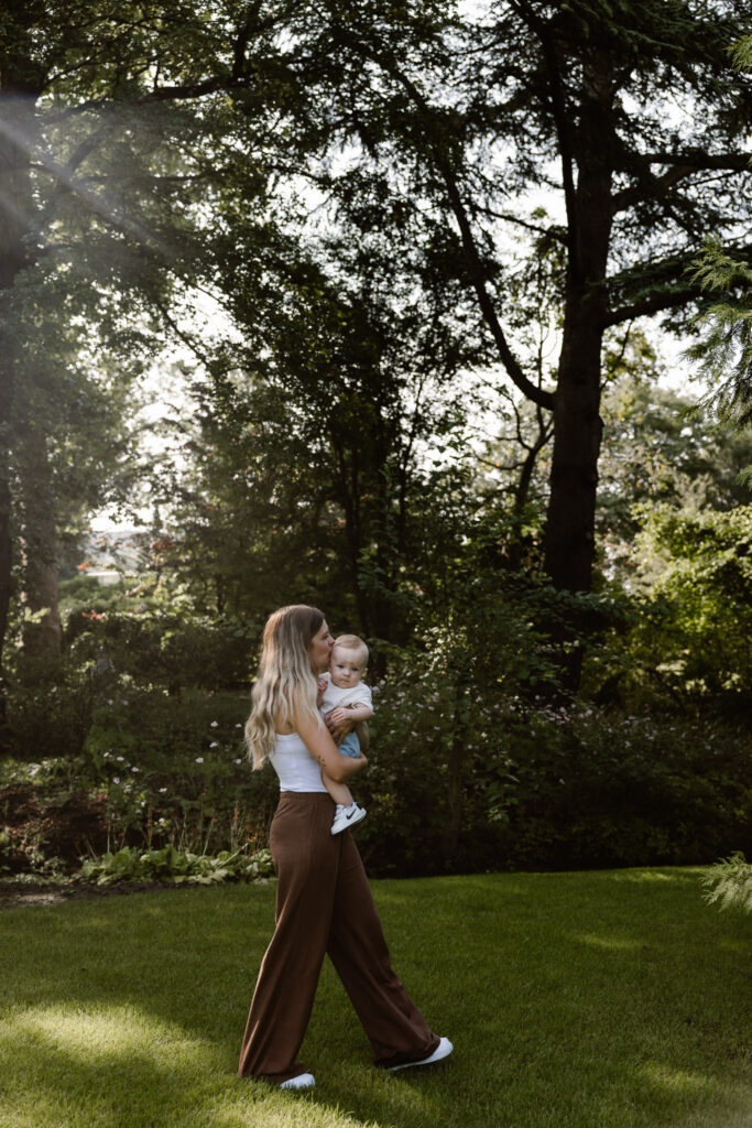 Lifestyle foto van een moeder die met haar baby over de paden van de Trompenburg Tuinen wandelt.