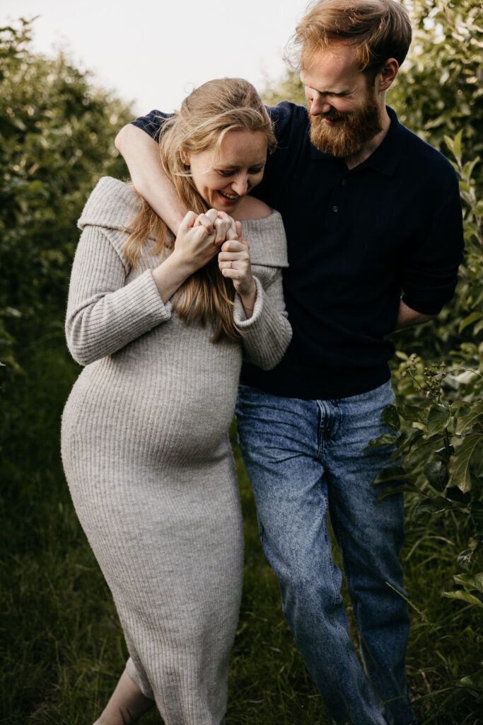 Aanstaand stel danst vrolijk in het gras tijdens hun zwangerschapsfotografie sessie in Rhoon.