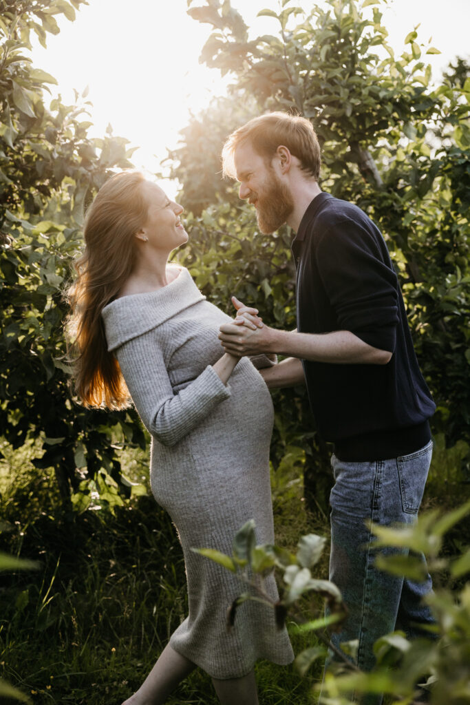 Aanstaand stel danst vrolijk in het gras tijdens hun zwangerschapsfotografie sessie in Rhoon.