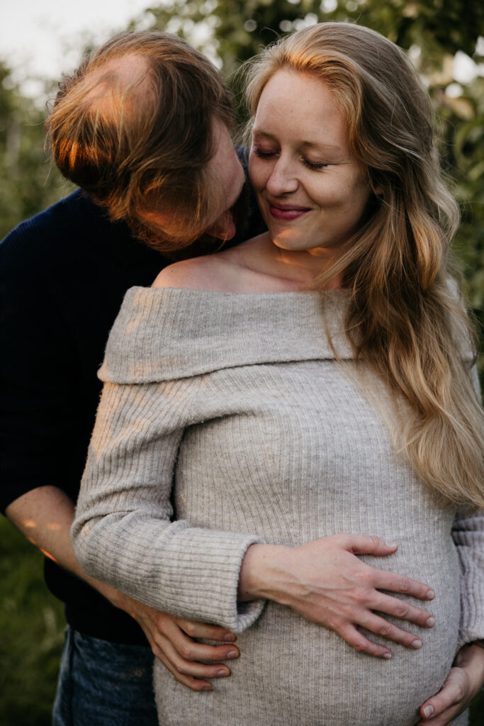 Aanstaande ouders houden elkaar teder vast tijdens hun zwangerschapsshoot in de natuur van Rhoon.