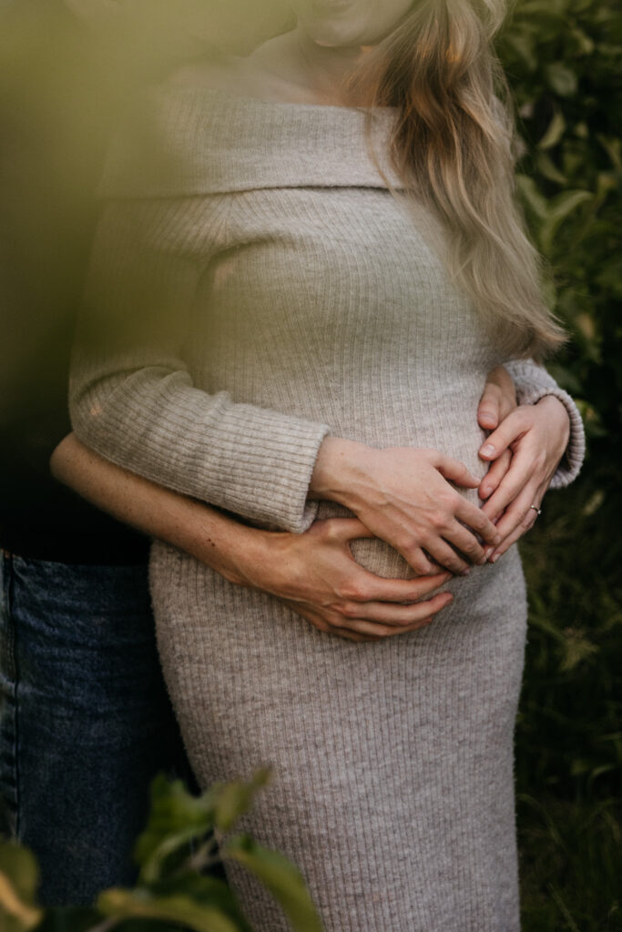 Detailfoto van babybuik tijdens een liefdevolle fotoshoot in de natuur bij Rotterdam.