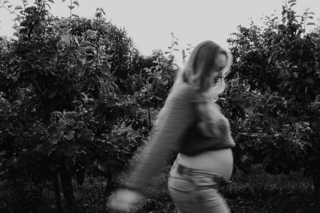 Ongedwongen en spontane foto van een zwangere vrouw die wandelt door de boomgaard in Rhoon.