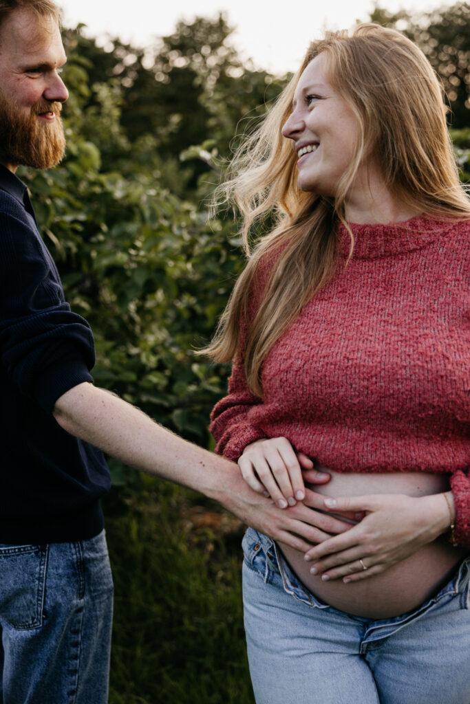 Aanstaand stel danst vrolijk in het gras tijdens hun zwangerschapsfotografie sessie in Rhoon.
