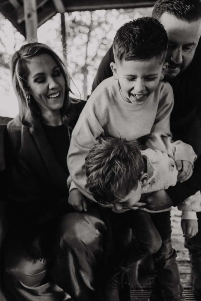 Familie knuffelt buiten op het gras tijdens een familie fotoshoot in Rotterdam.