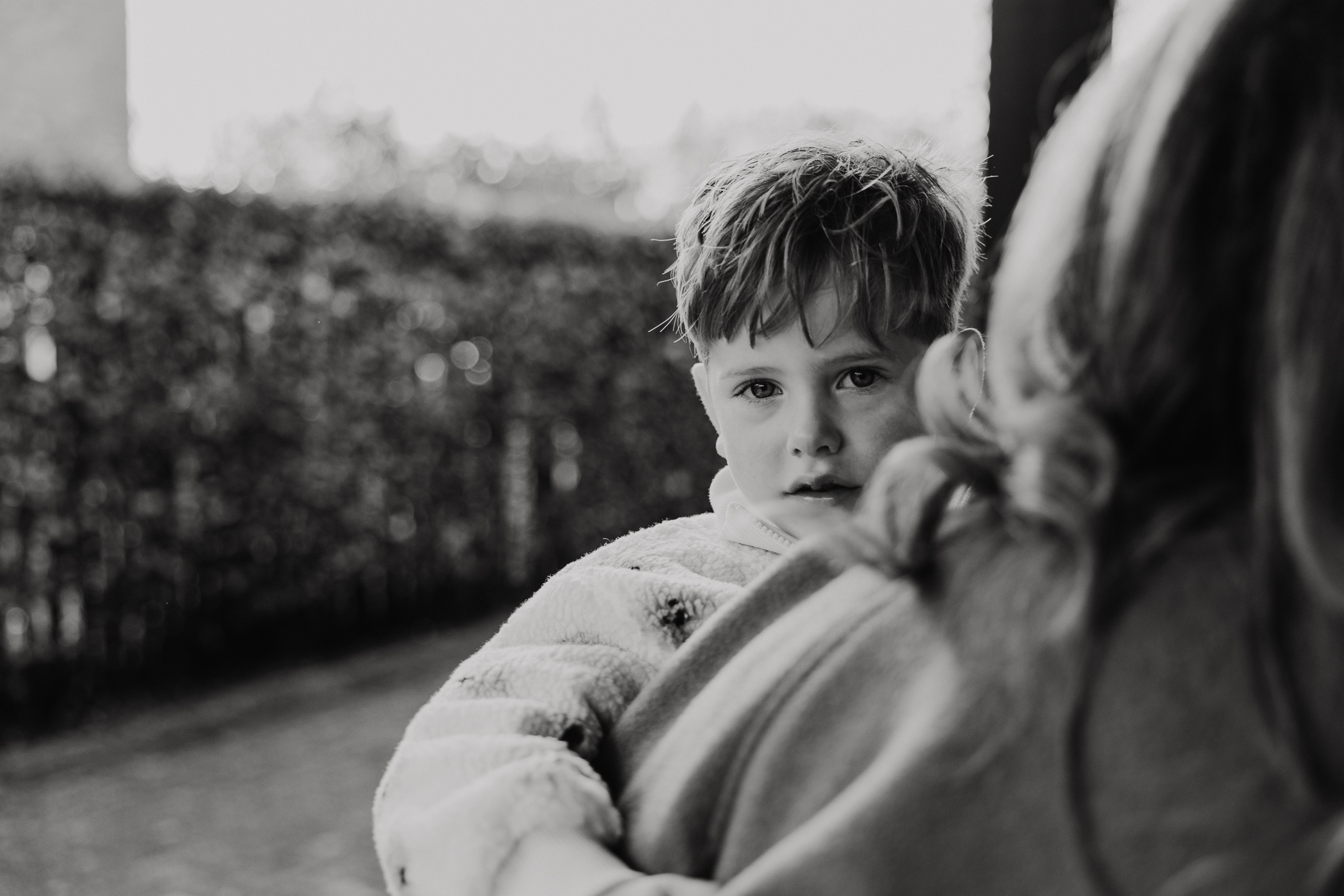 Broer en zus lachen samen in de tuin tijdens een huiselijke familieshoot.
