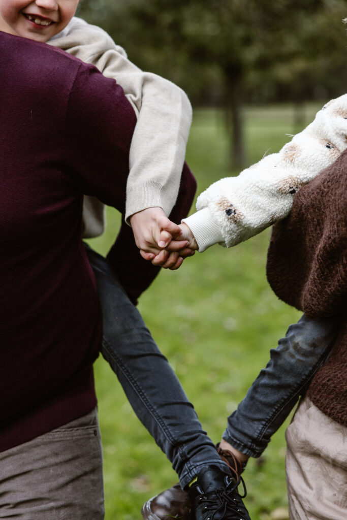 Broer en zus lachen samen in de tuin tijdens een huiselijke familieshoot.