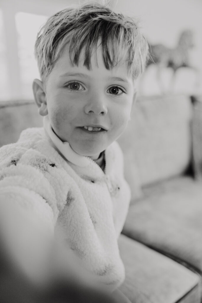 Twee kinderen springen op de bank bij opa en oma tijdens een huiselijke familieshoot.