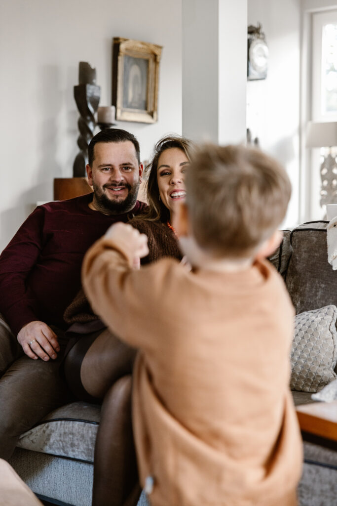 Gezin knuffelend op de bank bij opa en oma tijdens een huiselijke familieshoot.