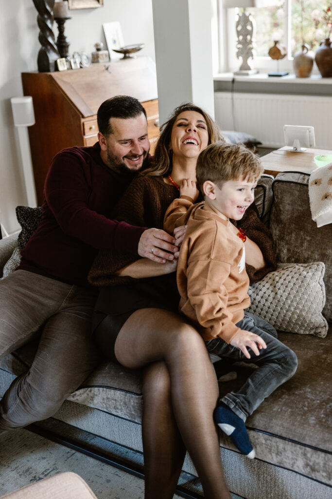 Gezin knuffelend op de bank bij opa en oma tijdens een huiselijke familieshoot.