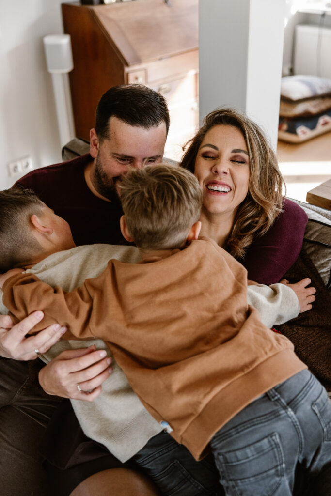 Gezin knuffelend op de bank bij opa en oma tijdens een huiselijke familieshoot.