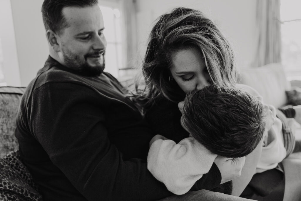 Gezin knuffelend op de bank bij opa en oma tijdens een huiselijke familieshoot.