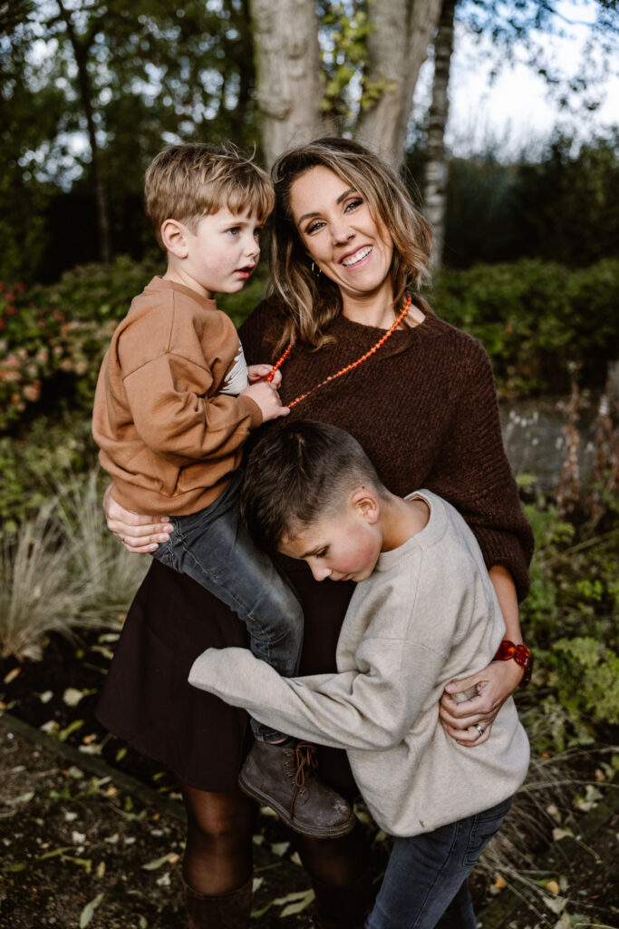 Mama met kinderen knuffelend buiten op het gras tijdens een familie fotoshoot in Rotterdam.