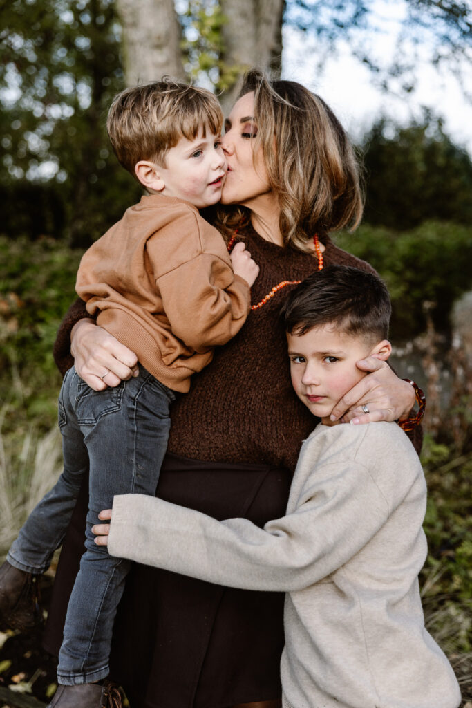 Mama met kinderen knuffelend buiten op het gras tijdens een familie fotoshoot in Rotterdam.