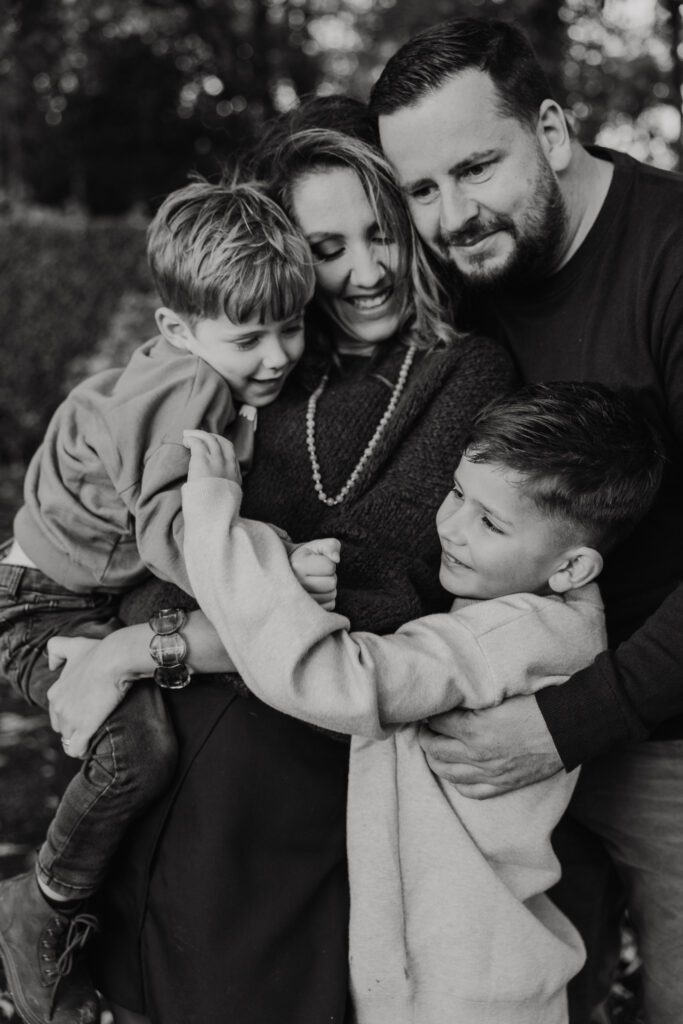 Familie knuffelt buiten op het gras tijdens een familie fotoshoot in Rotterdam.