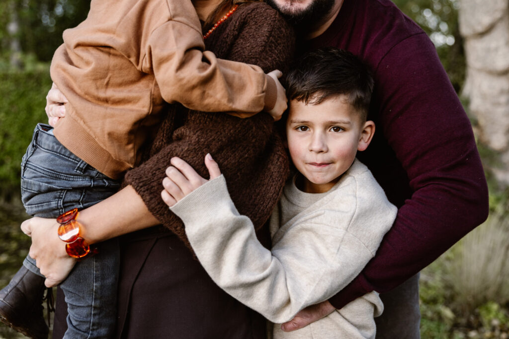 Familie knuffelt buiten op het gras tijdens een familie fotoshoot in Rotterdam.