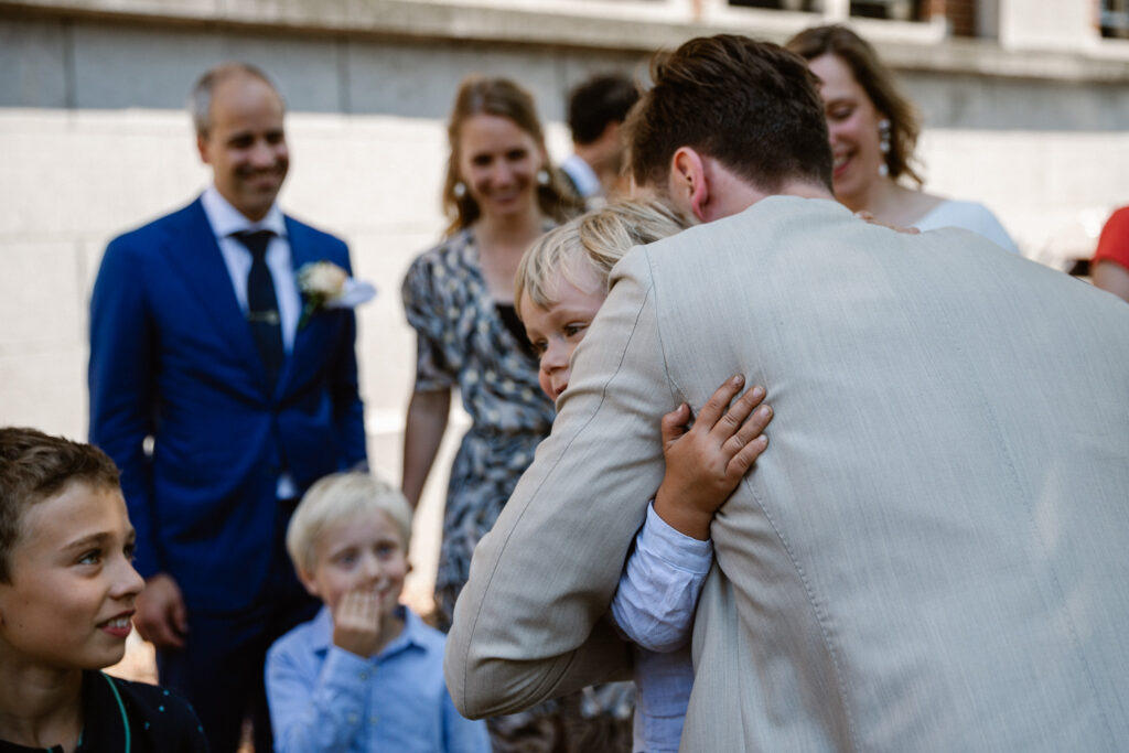 Kind knuffelt bruidegom tijdens borrelmoment, Muntgebouw Utrecht