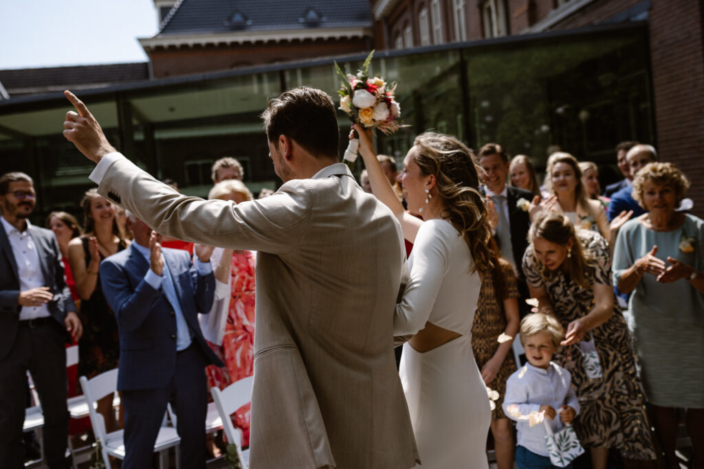 Bruidspaar omringd door gasten tijdens hun trouwceremonie in Utrecht stad.