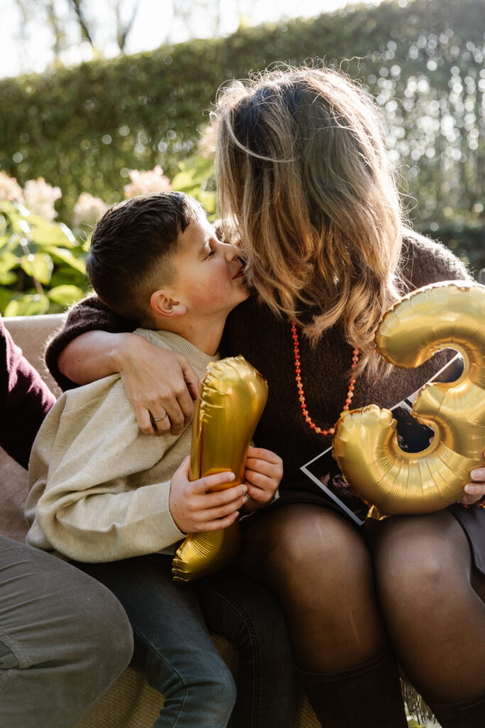Kinderen reageren enthousiast op baby aankondiging tijdens familieshoot bij opa en oma.