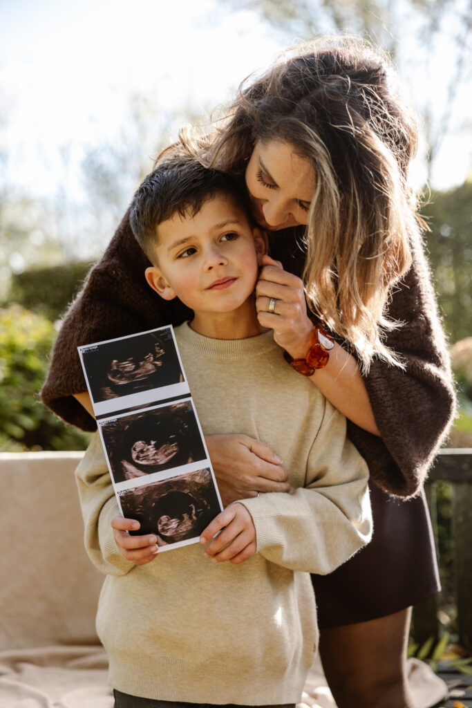 Gezin viert nieuws van een baby tijdens een liefdevolle familieshoot.