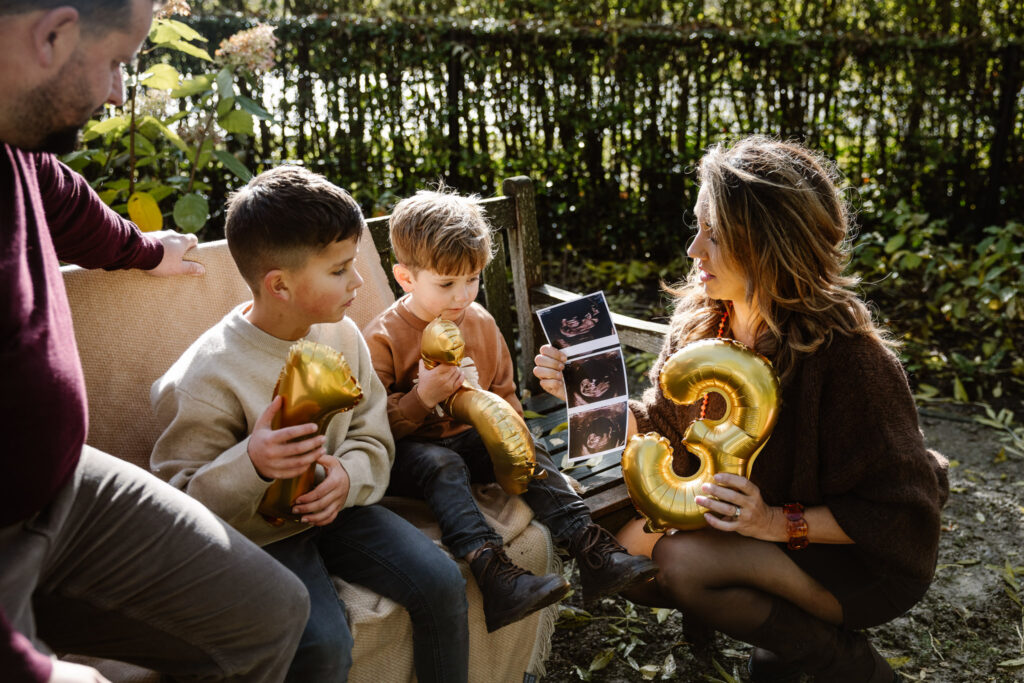 Ouders vertellen hun kinderen over zwangerschap tijdens een familie fotoshoot.